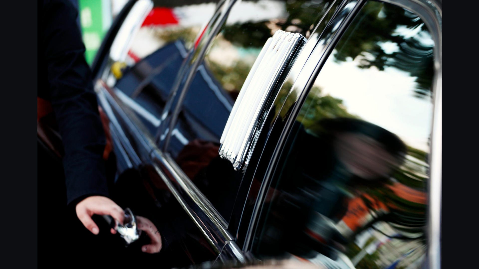 Luna chauffeur in dark suit, white-gloved hand resting on the rear door handle of an executive sedan