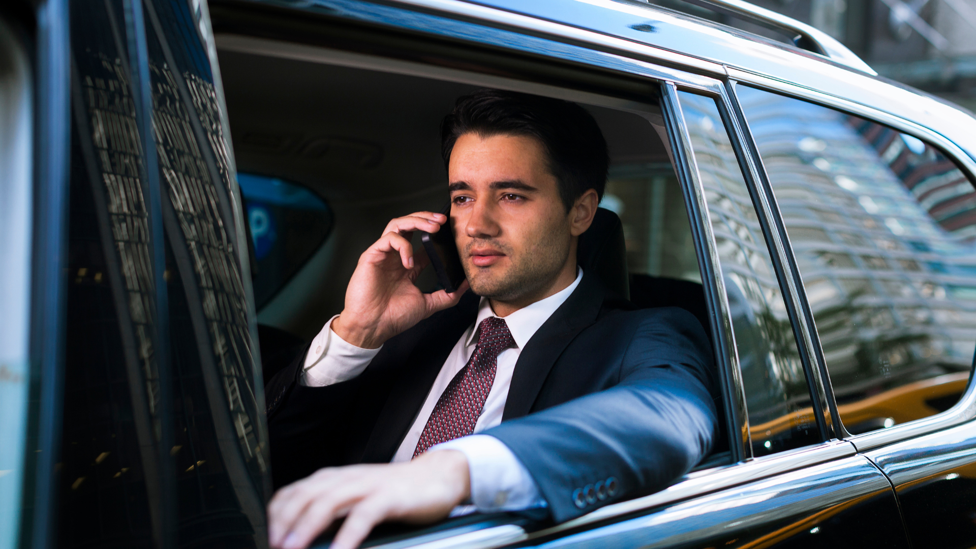 Executive in the back seat of a luxury sedan taking a call, calm and composed